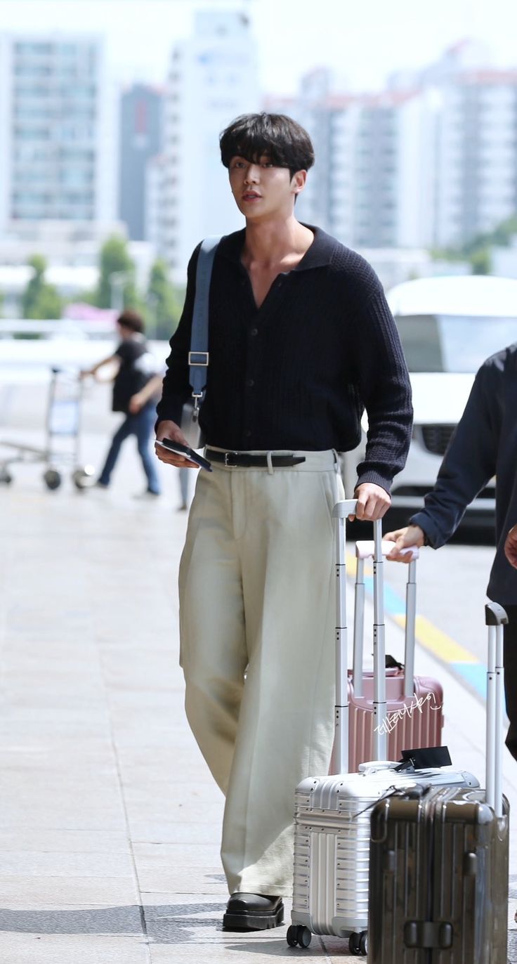 a man walking down the street with two pieces of luggage on his hand and one piece of luggage in his other hand