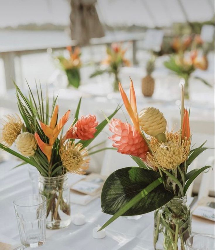 there are flowers in vases on the table at this wedding reception with white tables and chairs