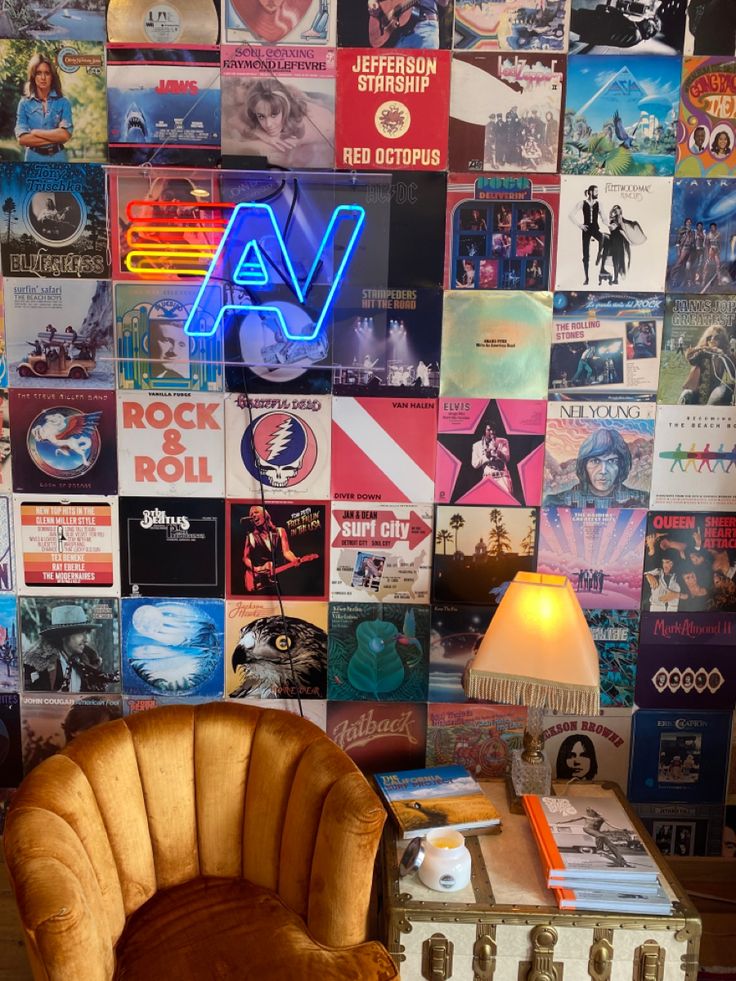 a chair sitting in front of a wall full of movies and posters on it's sides