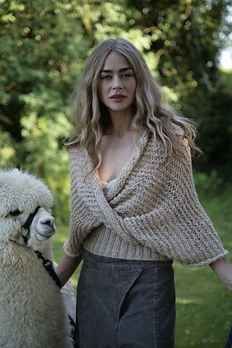 a woman standing next to a white llama