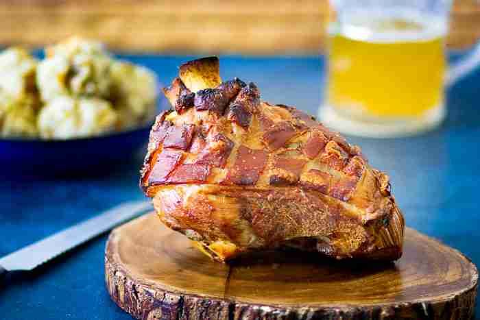 a piece of meat sitting on top of a wooden cutting board next to a bowl of potatoes