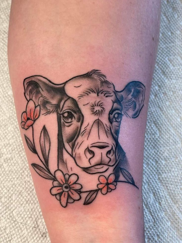 a black and white tattoo of a cow with flowers on it's side leg