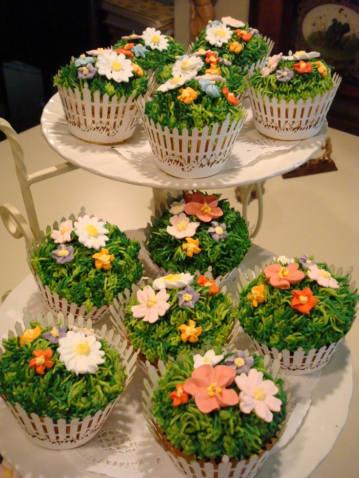 several cupcakes with flowers on them sitting on a cake stand