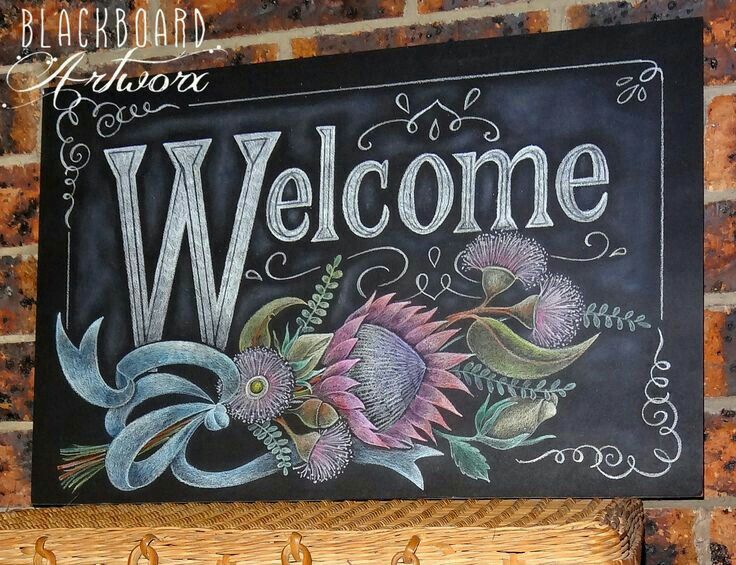 a welcome sign hanging on the side of a brick wall next to a wicker basket