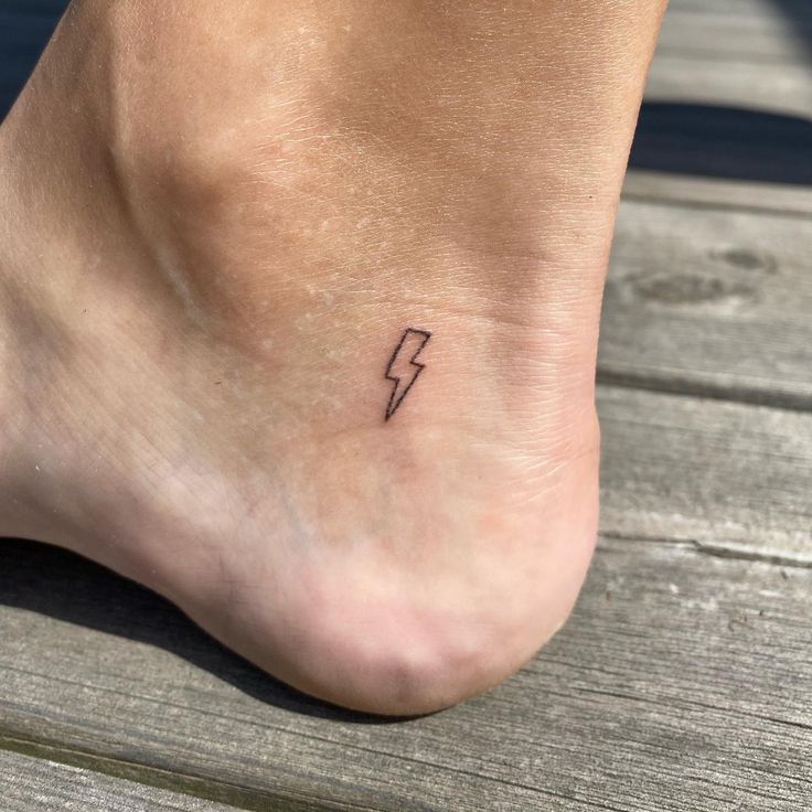 a small tattoo on the foot of a person with a lightning bolt in it's center