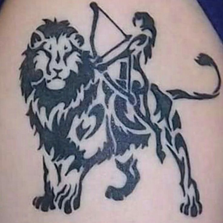 a lion tattoo on the back of a woman's shoulder with an arrow in it