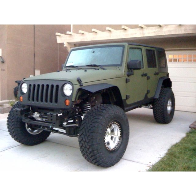 a green jeep parked in front of a garage