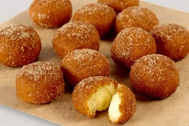 some sugared doughnuts are on a piece of parchment paper