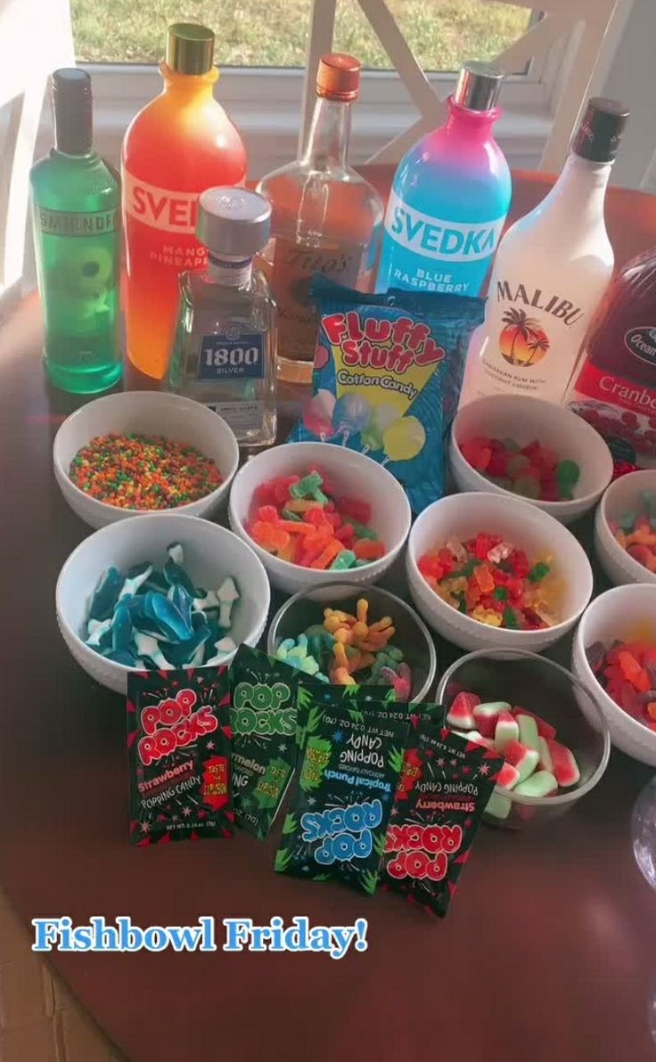 there are many drinks and candy in bowls on the table