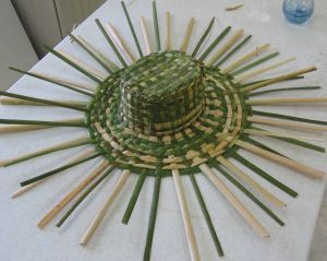 a green hat sitting on top of a white table next to wooden skewers