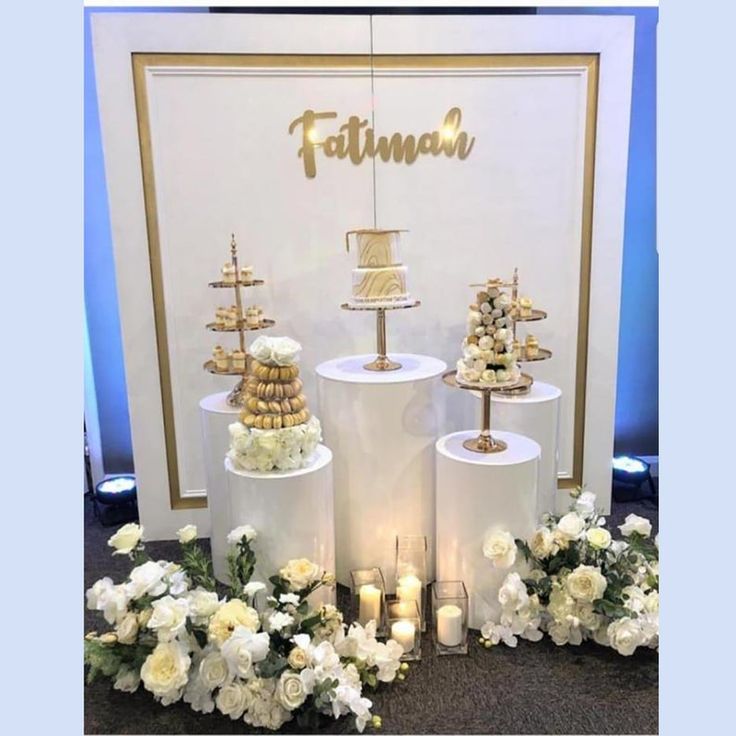 three tiered cake stands with white flowers and candles on the floor next to each other