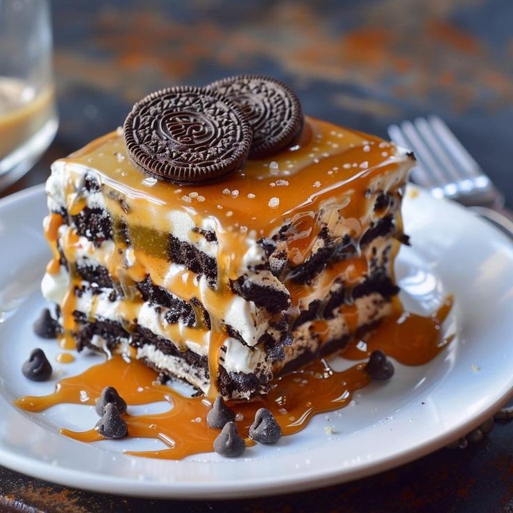 a piece of cake with oreo cookies on top and caramel drizzle