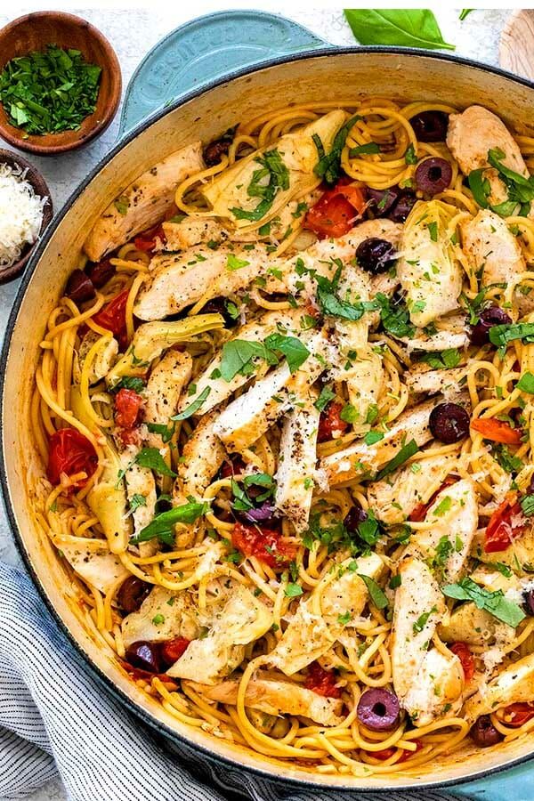 a skillet filled with chicken, olives and pasta