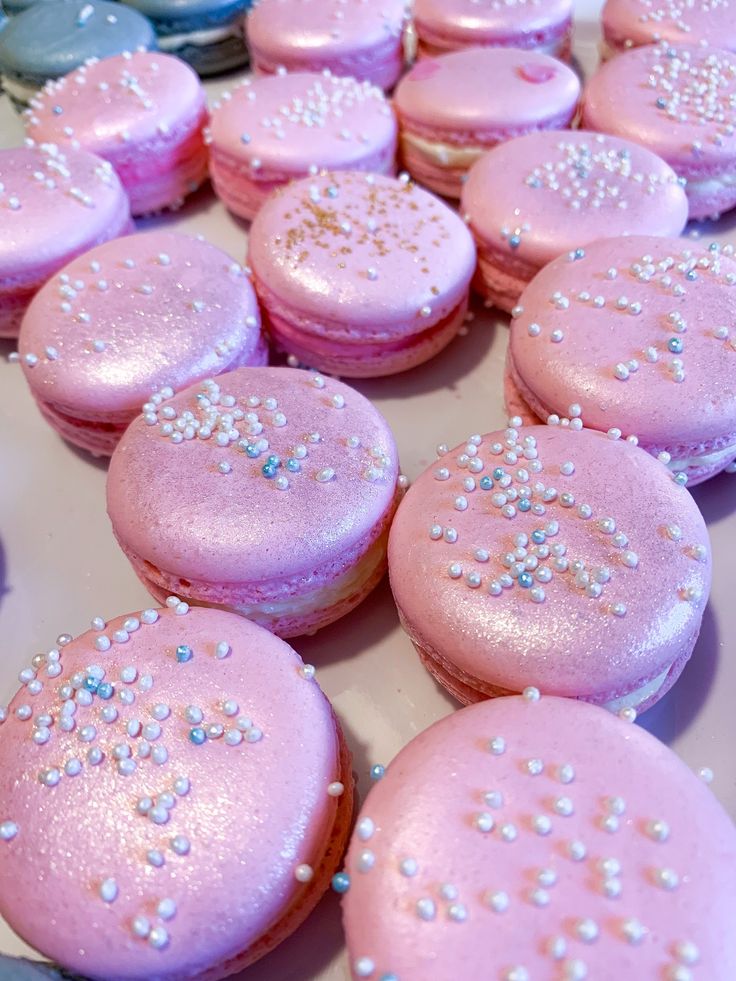 there are many pink macaroons with white and blue sprinkles on them