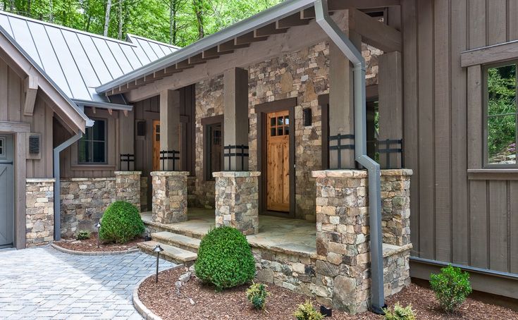 a house with stone walls and steps leading to the front door is surrounded by greenery