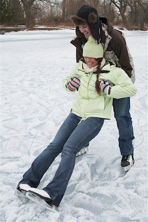 a man and woman riding on top of snow covered ground