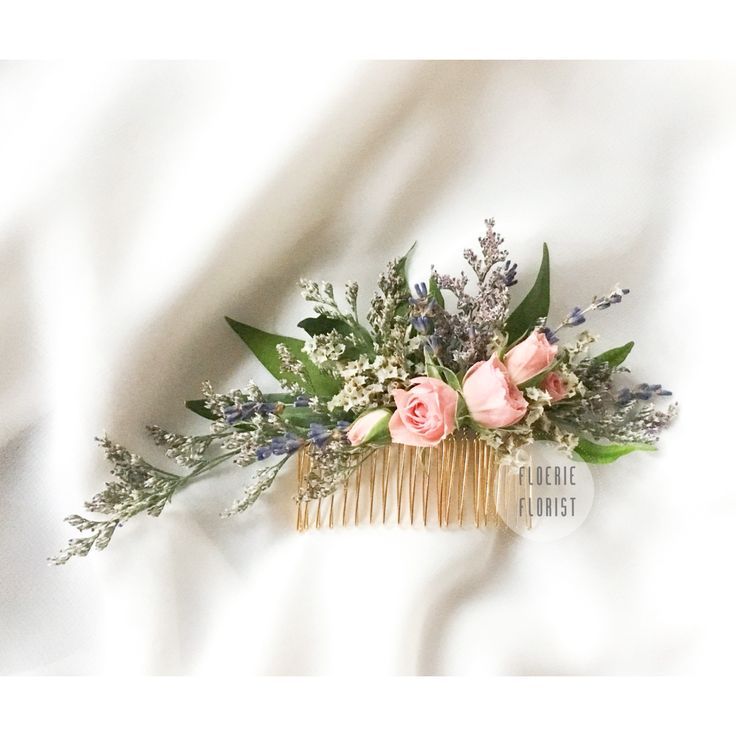 a hair comb with flowers and greenery in it sitting on a white bed sheet