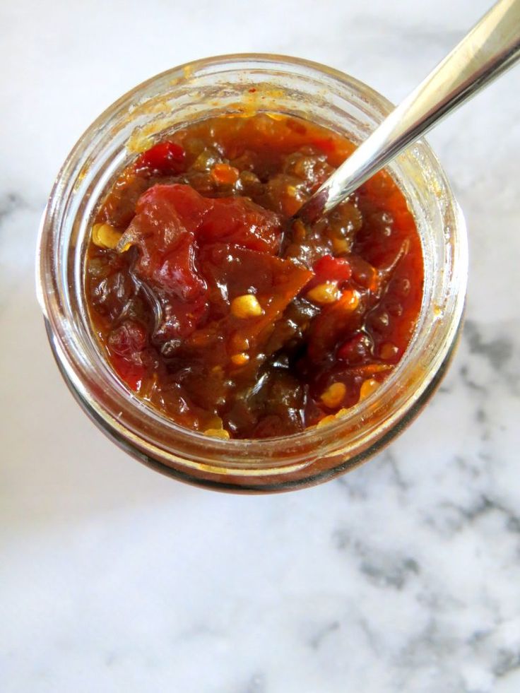 a jar filled with food sitting on top of a marble counter next to a spoon