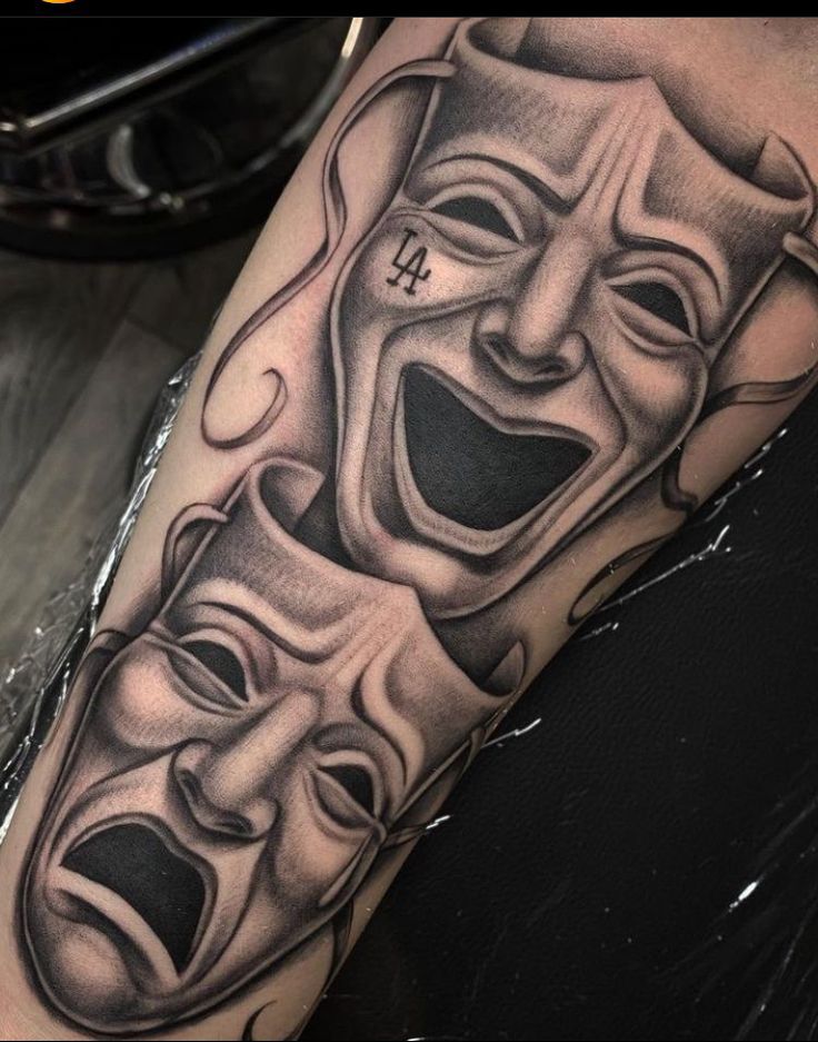 a tattoo with three masks on it