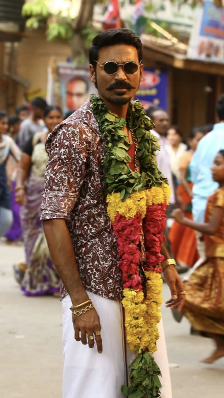 a man wearing a lei and standing in the middle of a street with people around him