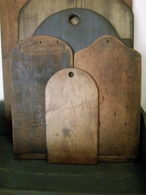 two wooden cutting boards sitting next to each other on top of a shelf in front of a wall