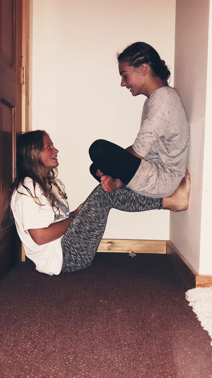 two women are sitting on the floor and one has her leg up in the air