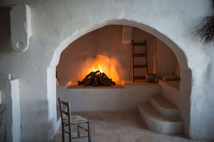 a fireplace in a room with stairs leading up to it and a chair next to it