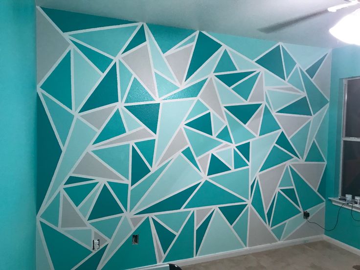 a room painted with blue and white geometric shapes on the wall, along with a window