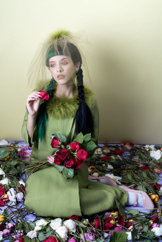 a doll sitting on top of a bed covered in flowers