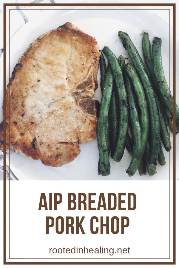 a white plate topped with meat and green beans next to a piece of pork chop