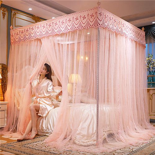 a woman is sitting in a bed with pink curtains on the headboard and foot board