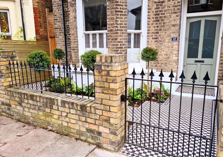 a brick house with an iron fence and flower boxes on the front porch, along with potted plants