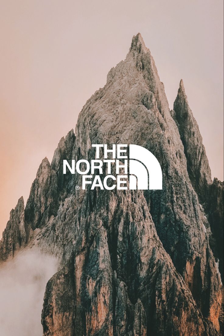 the north face logo on top of a mountain with clouds in the air behind it