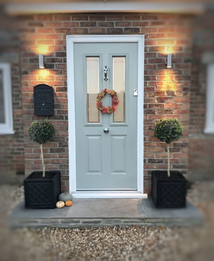 the front door is decorated with wreaths and potted plants