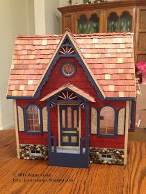 a small red and blue doll house on a wooden table