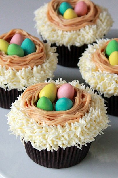 six cupcakes with chocolate frosting and eggs in the center on a white plate