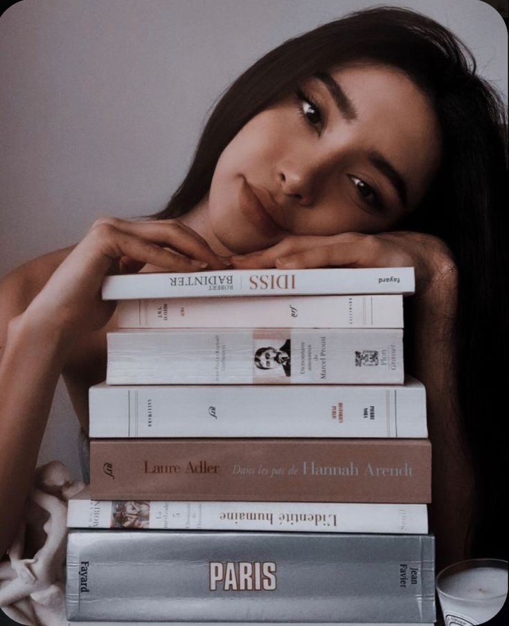 a woman leaning on top of a stack of books