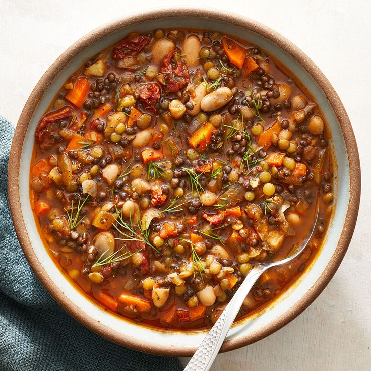 a bowl filled with beans, carrots and herbs