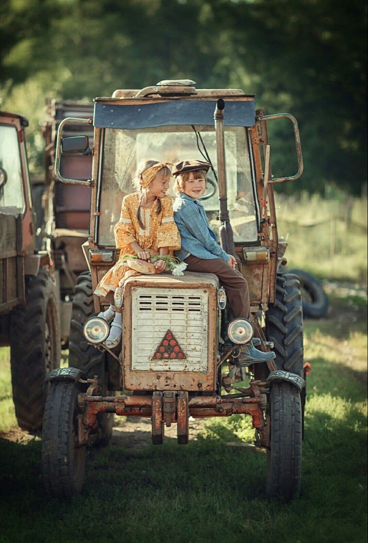 two people riding on the back of an old tractor