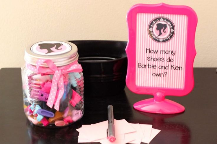 a jar filled with lots of candy sitting on top of a desk next to a sign that says how many sheets do barbie and ken own?