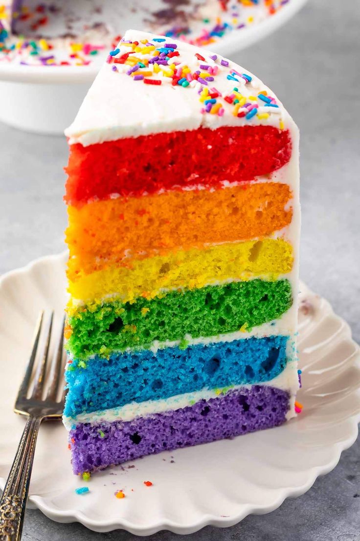 a slice of rainbow cake on a plate with a fork