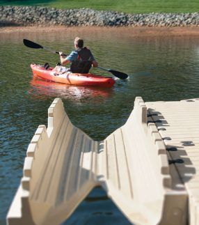 a man in a red kayak paddling on the water next to a dock