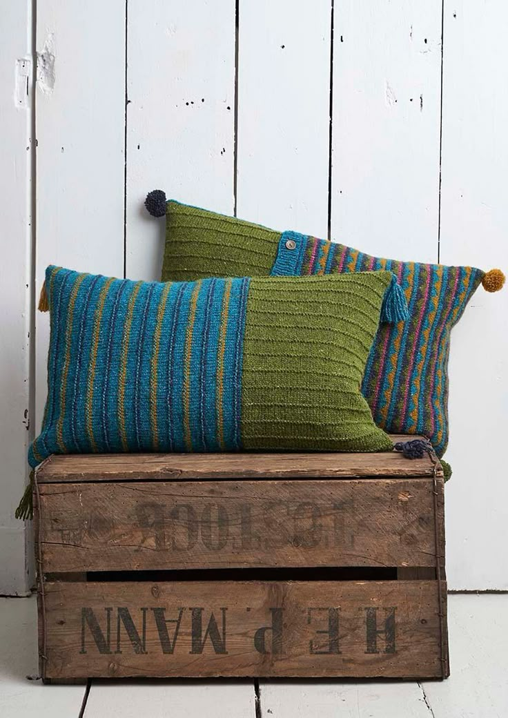 three pillows sitting on top of a wooden crate