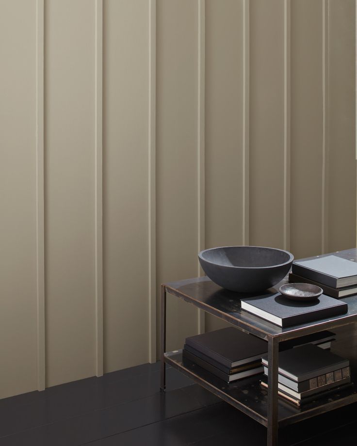 a black bowl sitting on top of a glass table next to a book shelf and window