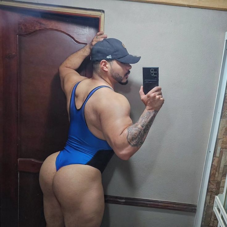 a man taking a selfie with his cell phone while wearing a blue swimsuit