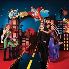 a man and woman posing for a photo in front of a backdrop with superheros