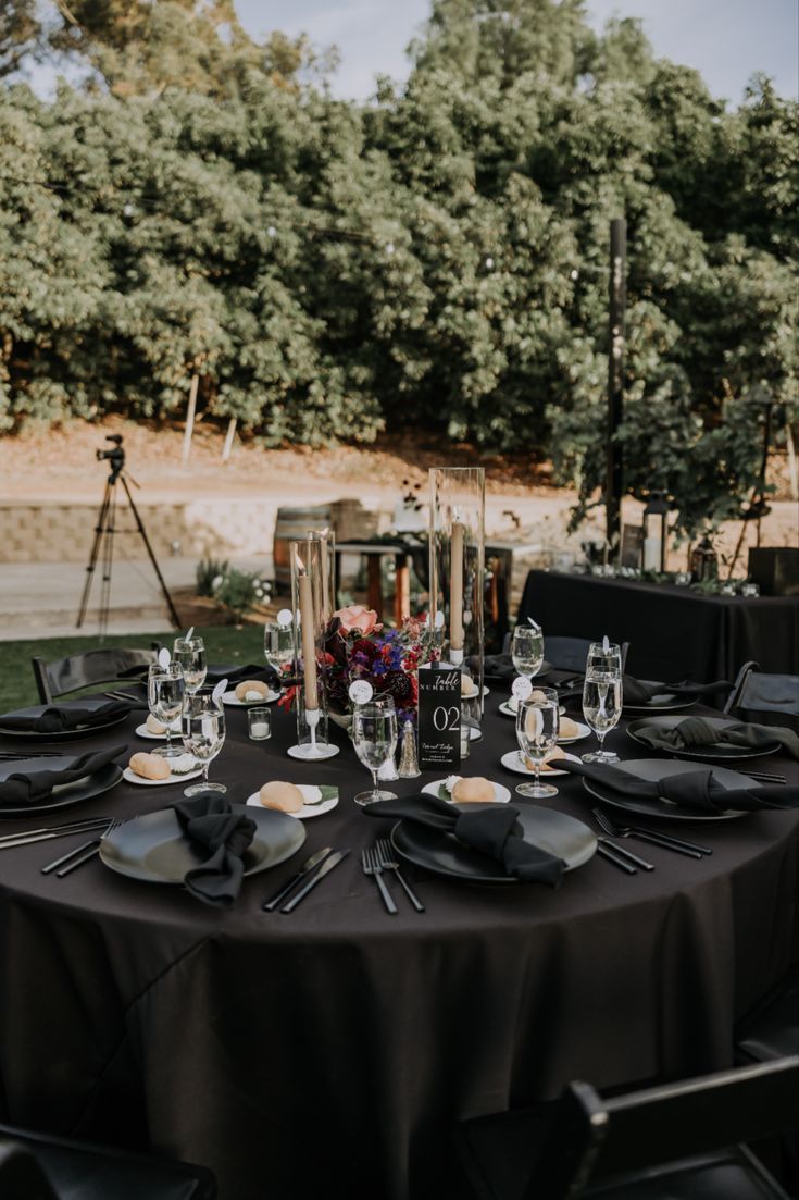 a table set with black plates and place settings