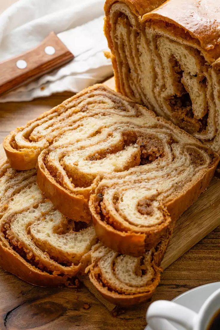 sliced cinnamon roll sitting on top of a wooden cutting board