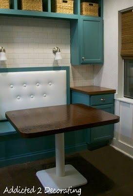 an empty kitchen with blue cabinets and white counter tops, along with a wooden table in the center