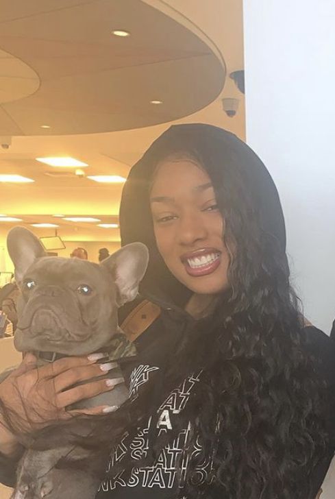 a woman is holding a dog in her arms and smiling at the camera while wearing a hoodie